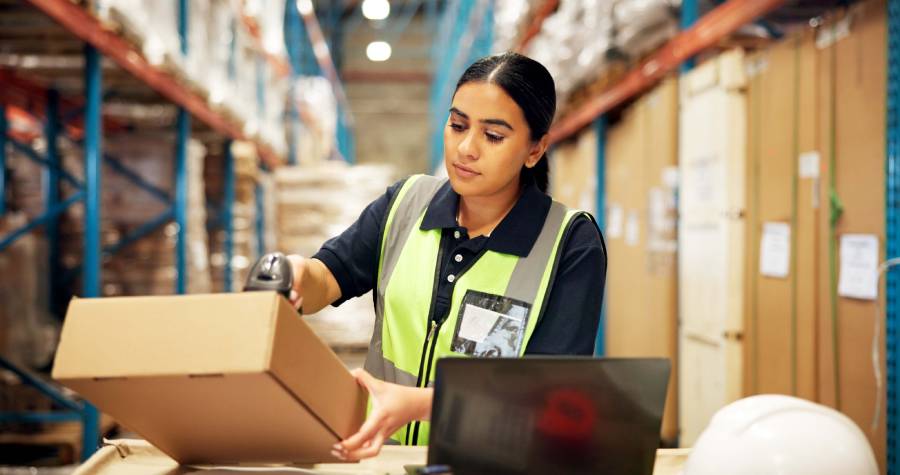 Operadora de logística escaneando caixas em depósito, representando o volume de vendas necessário para alcançar o selo MercadoLíder