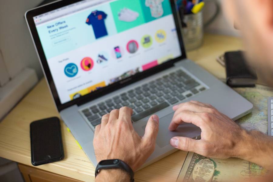 Pessoa usando laptop para gerenciar anúncios em marketplace em plataforma de e-commerce com produtos à venda na tela.