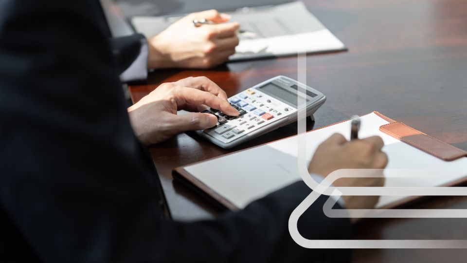 M&atilde;os calculando na calculadora e escrevendo em bloco de notas durante reuni&atilde;o sobre recupera&ccedil;&atilde;o de valores.