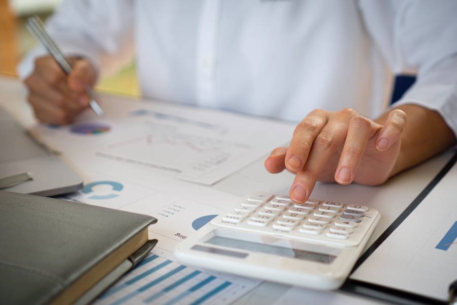 Mãos usando calculadora e caneta para analisar recuperação de valores
